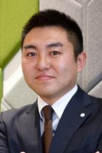 模様のある背景のスーツを着た人がカメラを見つめています。